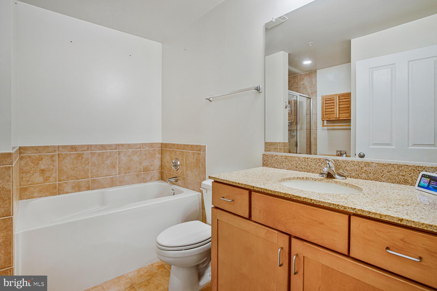 414 Water Street, Unit 2913 Baltimore, MD 21202 - Photo 14 of 41 a bathroom with a granite countertop sink a toilet and bathtub