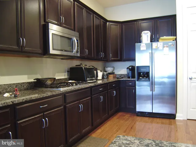 a kitchen with granite countertop wooden cabinets and stainless steel appliances