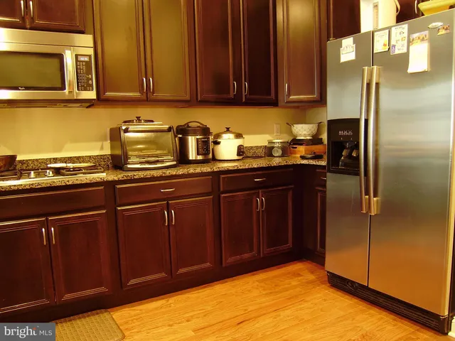 a kitchen with stainless steel appliances granite countertop wooden cabinets a refrigerator and a sink