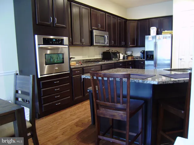 a kitchen with granite countertop wooden cabinets and stainless steel appliances