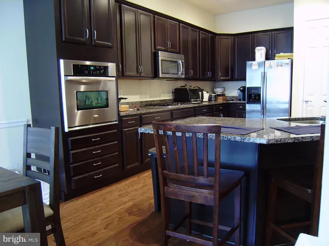a kitchen with granite countertop wooden cabinets and stainless steel appliances