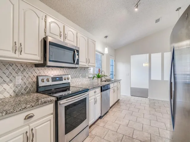 a kitchen with stainless steel appliances granite countertop a stove microwave and refrigerator