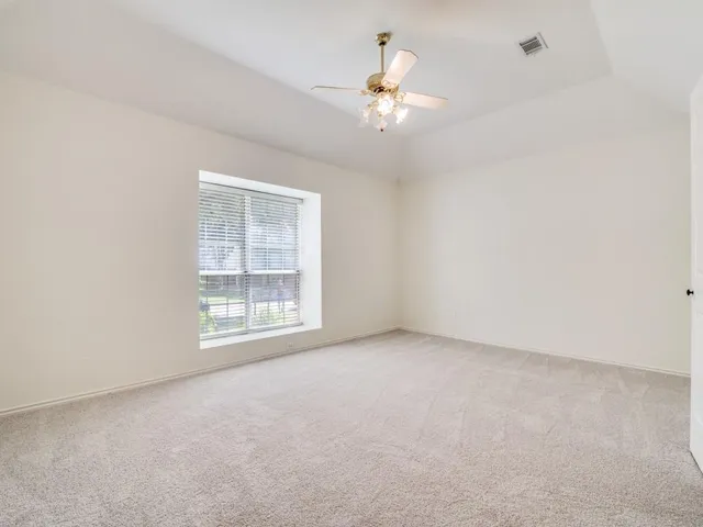 an empty room with a chandelier fan and windows