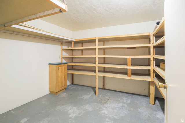 634 South 2100th Street West Vernal, UT 84078 - Photo 32 of 71 Ample storage room featuring extensive built-in wooden shelving, a light wood-finish base cabinet with a dark countertop, and durable concrete flooring