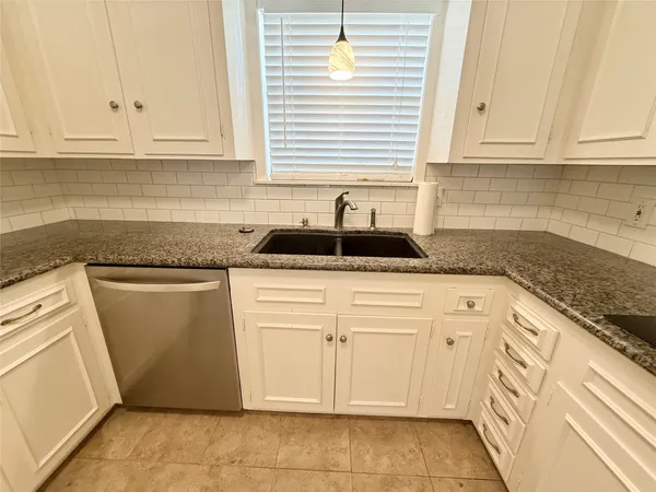 a kitchen with granite countertop white cabinets and sink