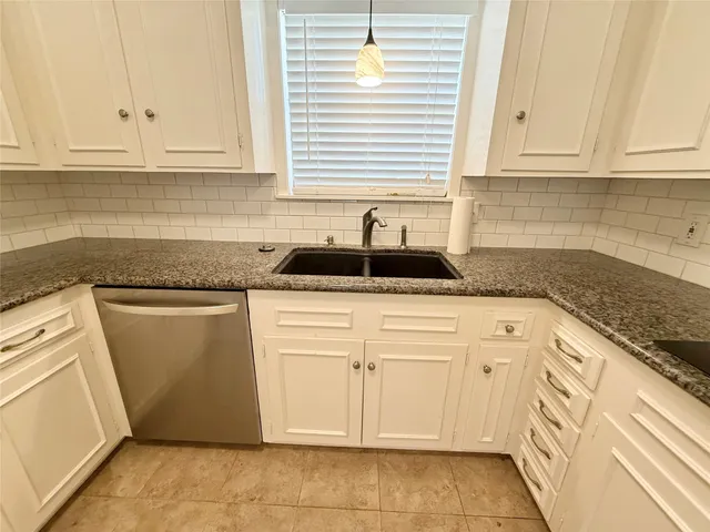 a kitchen with granite countertop white cabinets and sink