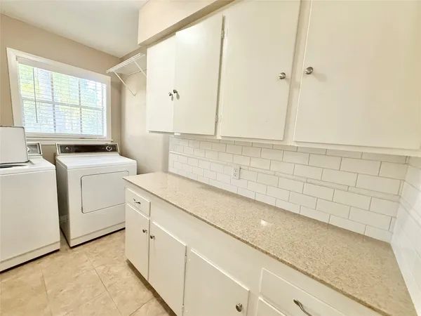 a view of a kitchen with white cabinets washer and dryer
