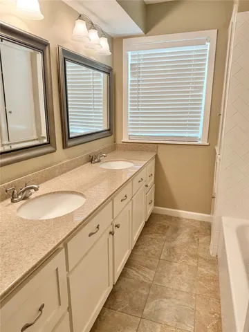 a bathroom with a granite countertop sink and a window