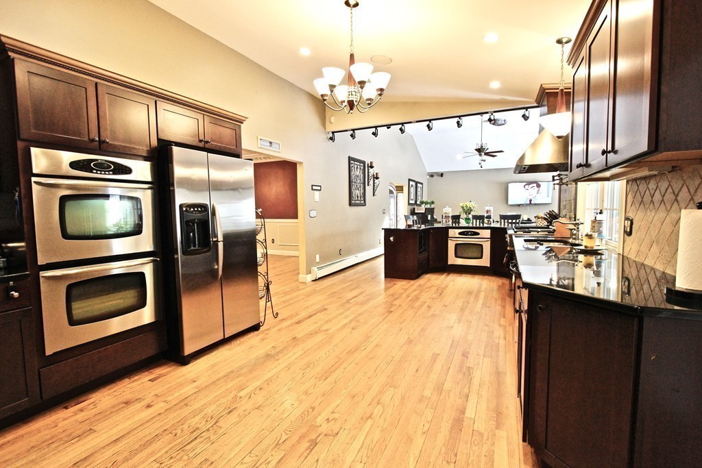 70 Summer Street Stoneham, MA 02180 - Photo 11 of 30 a kitchen with stainless steel appliances kitchen island granite countertop a stove top oven and sink