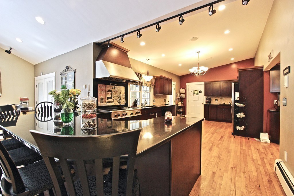 70 Summer Street Stoneham, MA 02180 - Photo 8 of 30 a kitchen with stainless steel appliances kitchen island granite countertop a table chairs in it and wooden floor