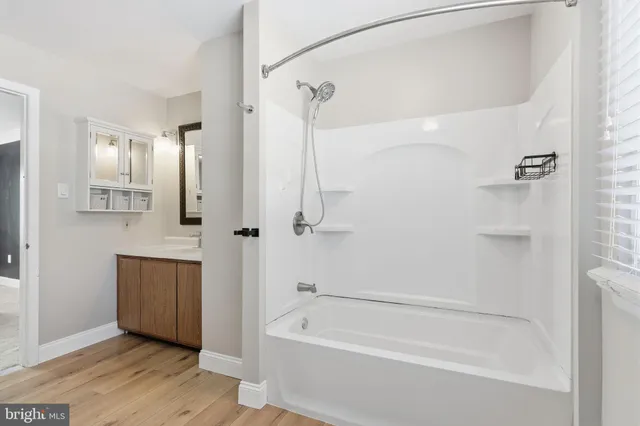 a bathroom with a tub shower vanity and a sink
