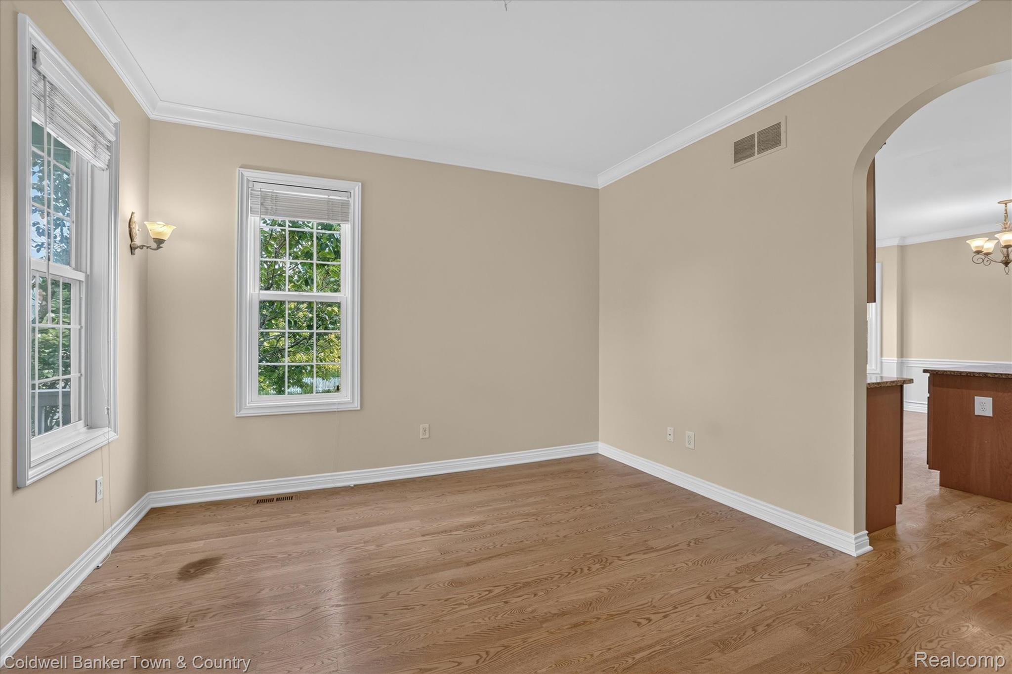 1725 Town Commons Drive Howell, MI 48855 - Photo 12 of 53 Room featuring wood-finish flooring, two large windows with grid patterns, and crown molding