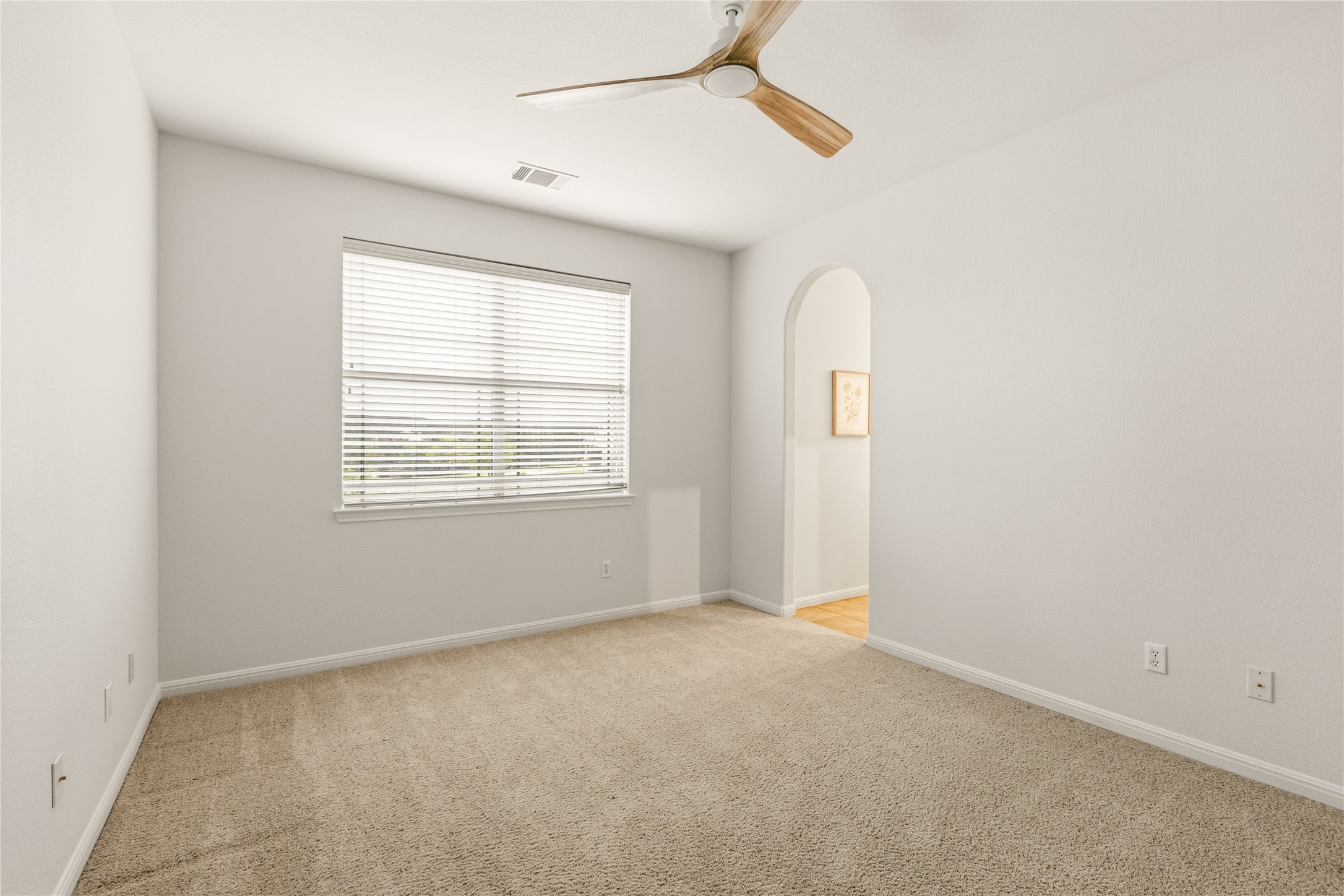 1432 Tom Sawyer Road Austin, TX 78737 - Photo 28 of 33 A well-lit bedroom features plush carpeting, a wide window with blinds, and a modern ceiling fan.