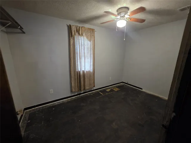 en empty room with windows and fan