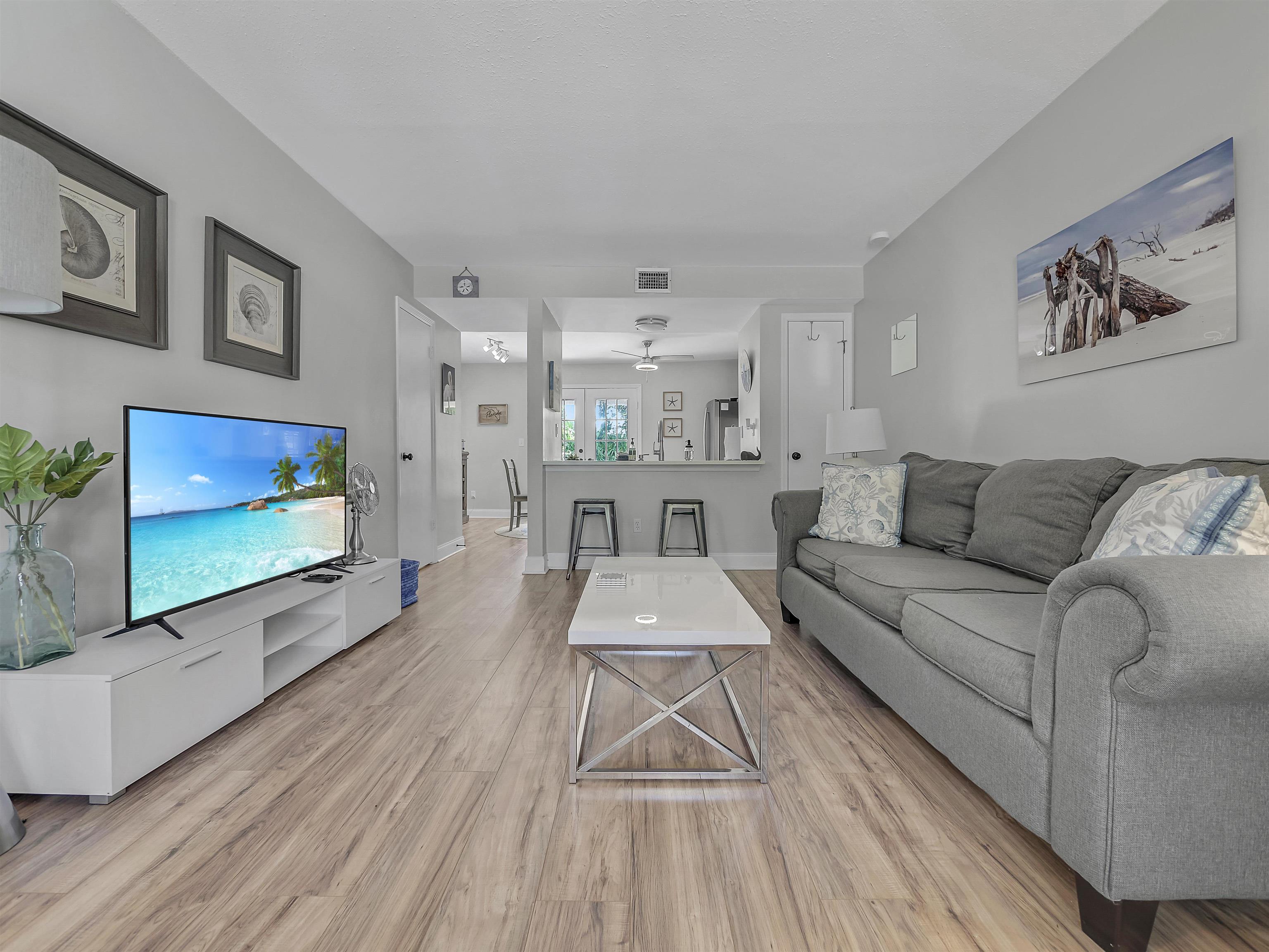 6444 Madison Street St. Augustine, FL 32080 - Photo 2 of 36 a living room with furniture a flat screen tv and a floor to ceiling window