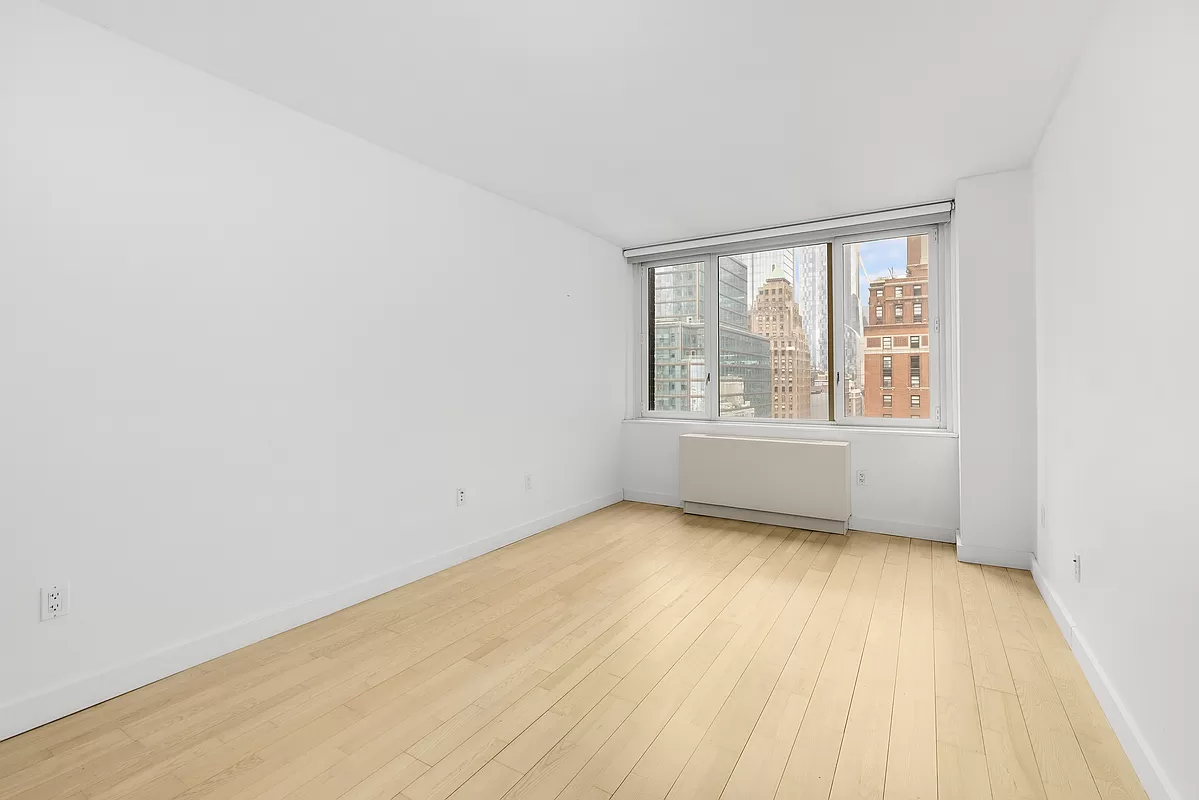 322 West 57th Street, Unit 25H Manhattan, NY 10019 - Photo 3 of 9 an empty room with wooden floor and windows