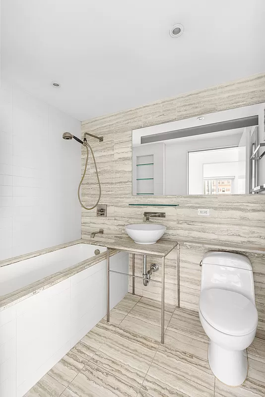 322 West 57th Street, Unit 25H Manhattan, NY 10019 - Photo 4 of 9 a bathroom with a toilet a sink and mirror