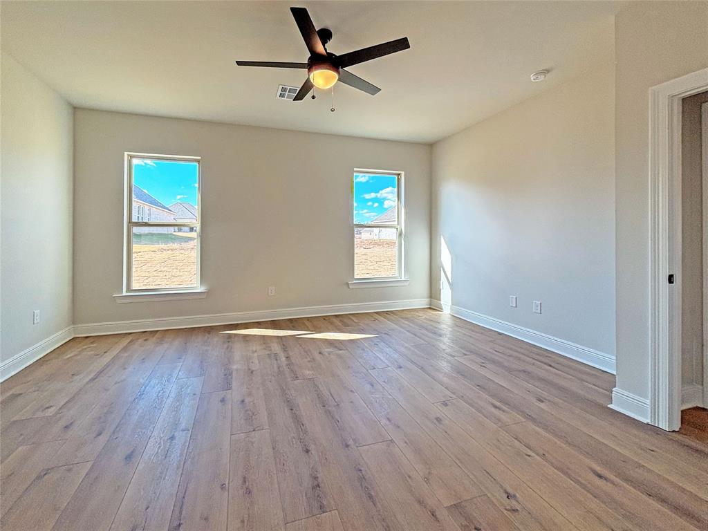 406 Hummingbird Lane Princeton, LA 71067 - Photo 17 of 25 an empty room with wooden floor ceiling fan and windows