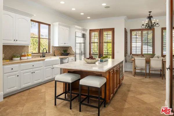 a large kitchen with kitchen island granite countertop a table chairs sink and cabinets