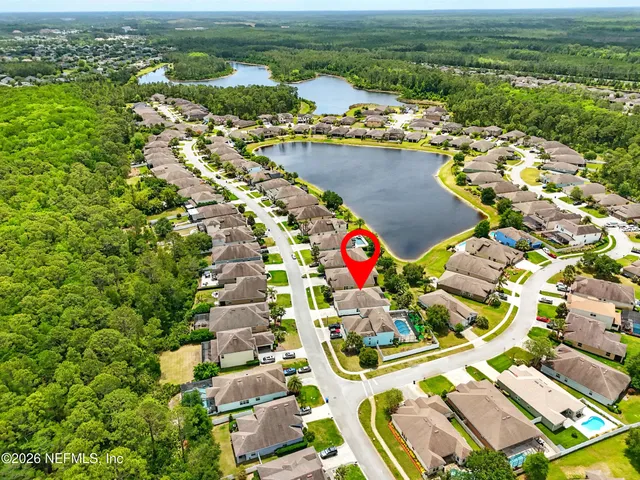 a view of a white house next to a yard with potted plants