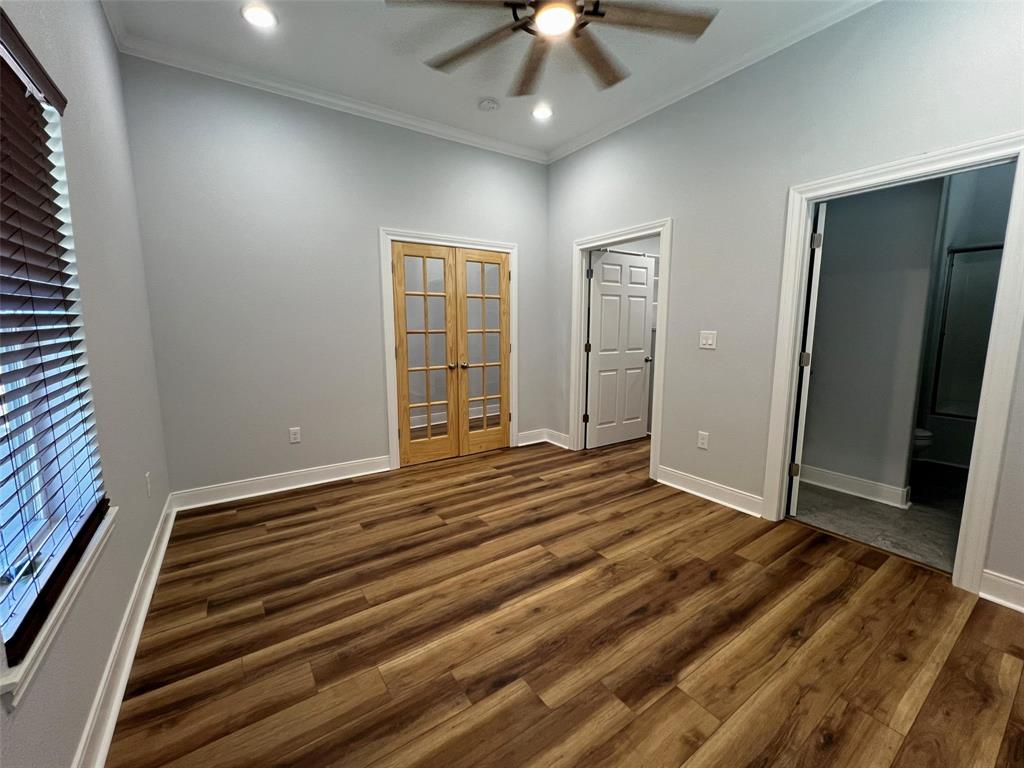 724 Franklin Street Bellevue, TX 76228 - Photo 17 of 32 en empty room with wooden floor chandelier fan and windows