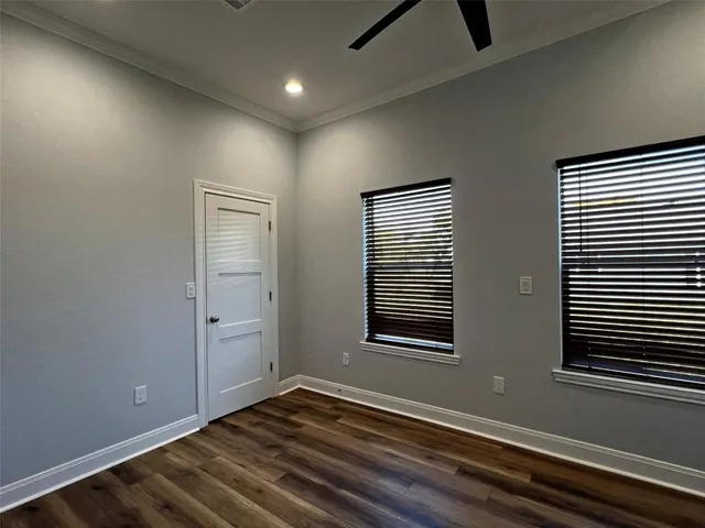an empty room with wooden floor cabinet and windows