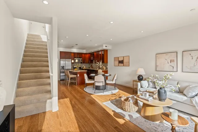 a living room with furniture kitchen view and a wooden floor