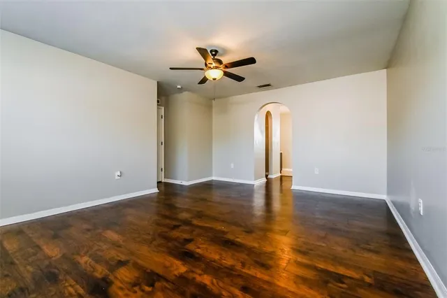 an empty room with wooden floor ceiling fan and window