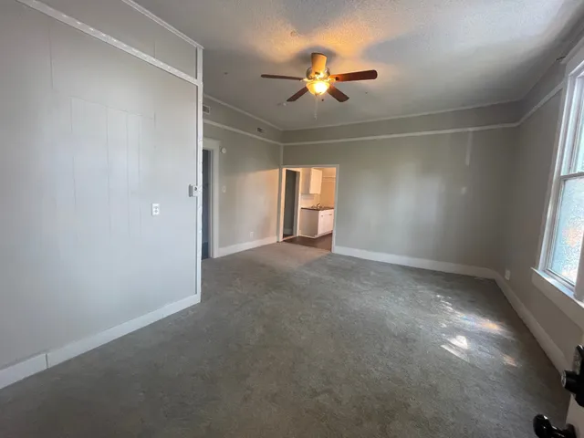 an empty room with windows and chandelier fan