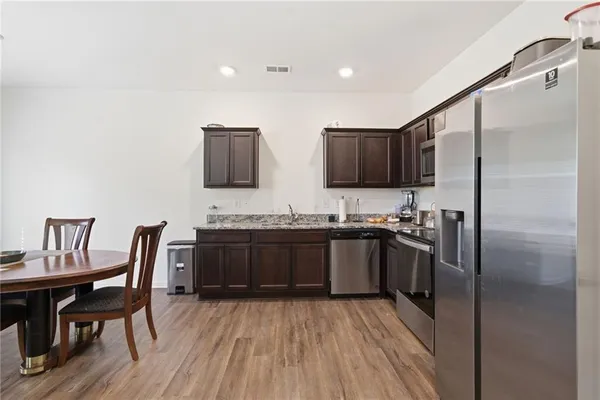 a kitchen with stainless steel appliances granite countertop a refrigerator a stove a sink and a microwave with wooden floor