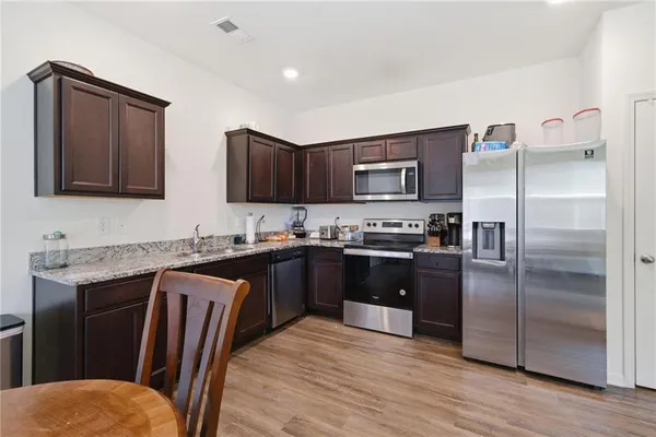 a kitchen with stainless steel appliances granite countertop a refrigerator a stove a sink and a microwave