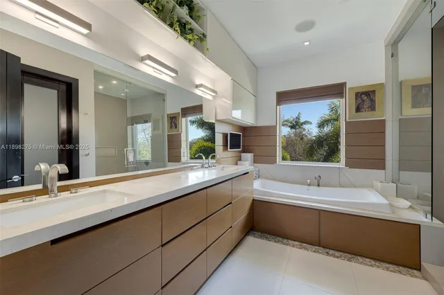 a bathroom with a large tub double vanity sink and a large mirror