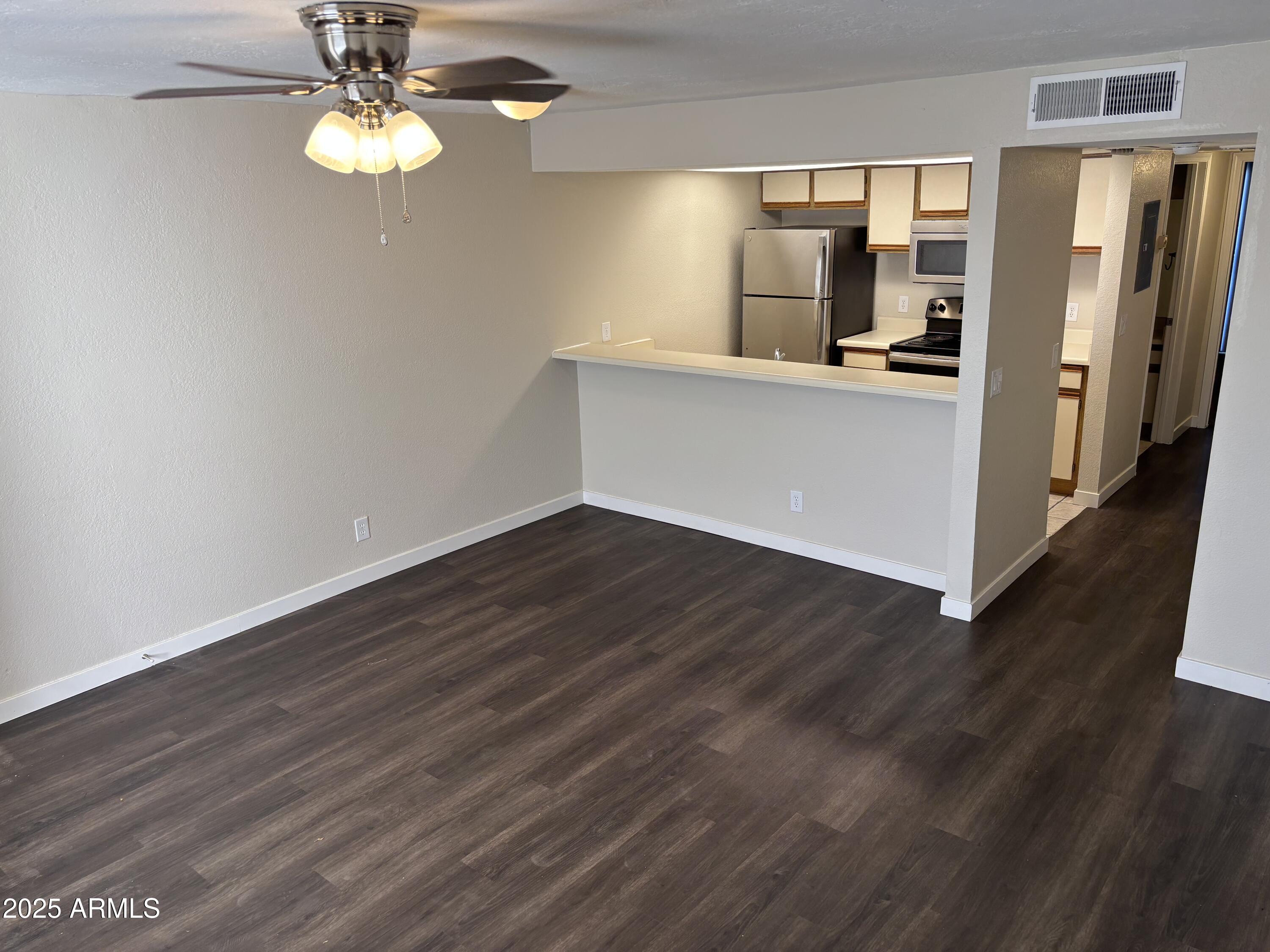 1444 North Recker Road, Unit 118 Mesa, AZ 85205 - Photo 3 of 22 a view of a kitchen with wooden floor and a ceiling fan