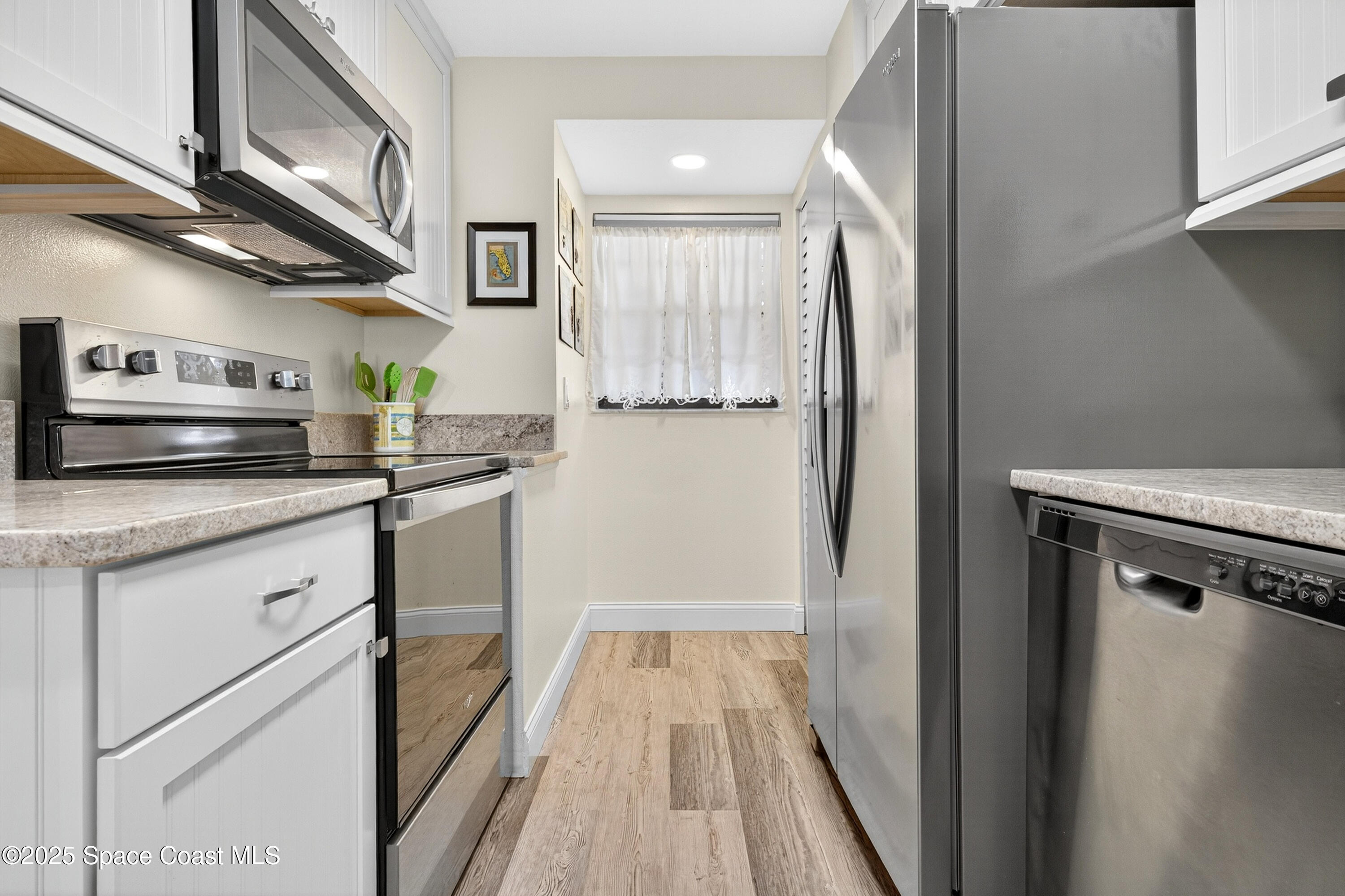 383 North Atlantic Avenue, Unit 105 Cocoa Beach, FL 32931 - Photo 11 of 67 a kitchen with stainless steel appliances granite countertop a refrigerator and a sink