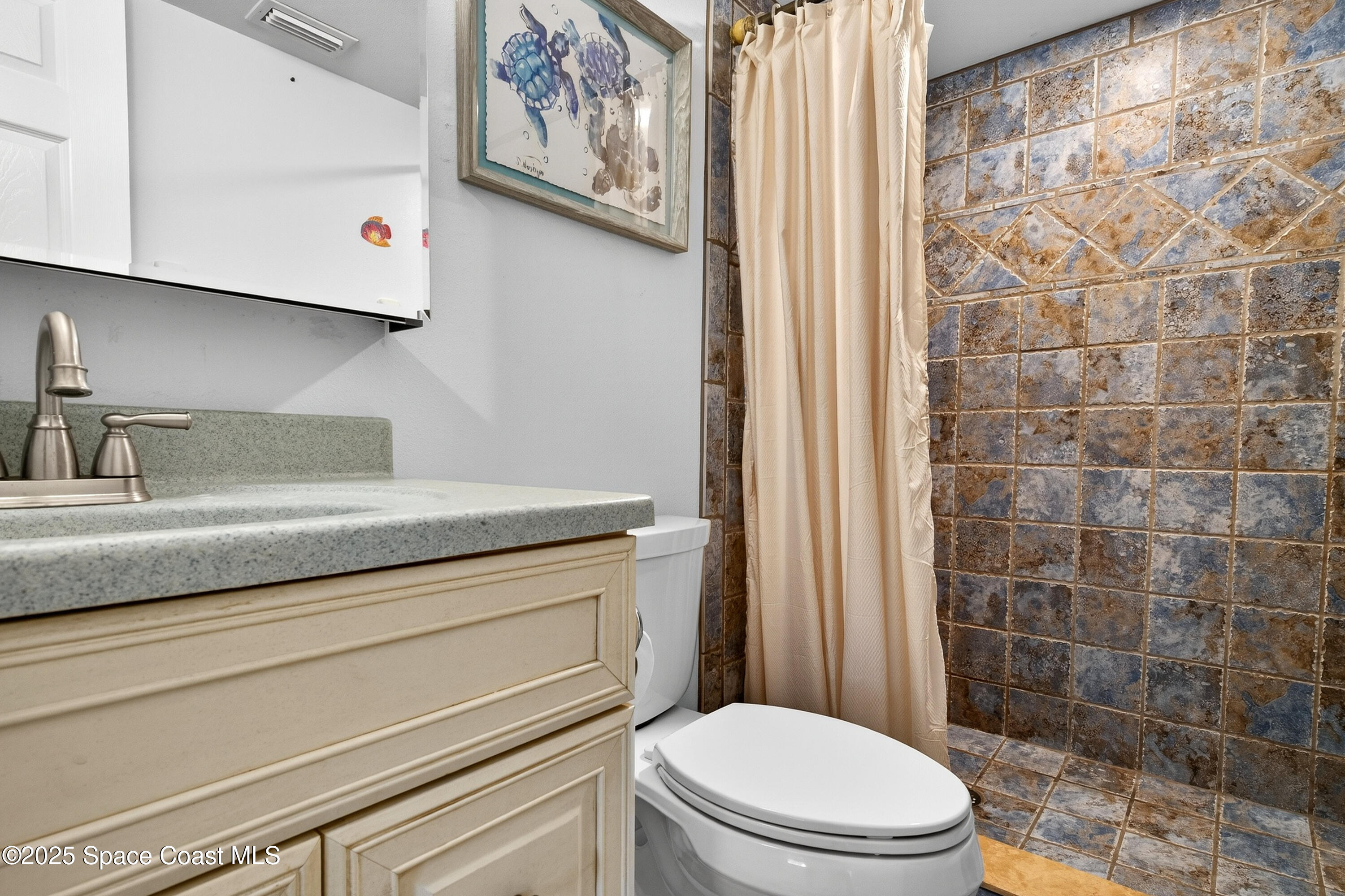 383 North Atlantic Avenue, Unit 105 Cocoa Beach, FL 32931 - Photo 34 of 67 a bathroom with a toilet and shower curtain