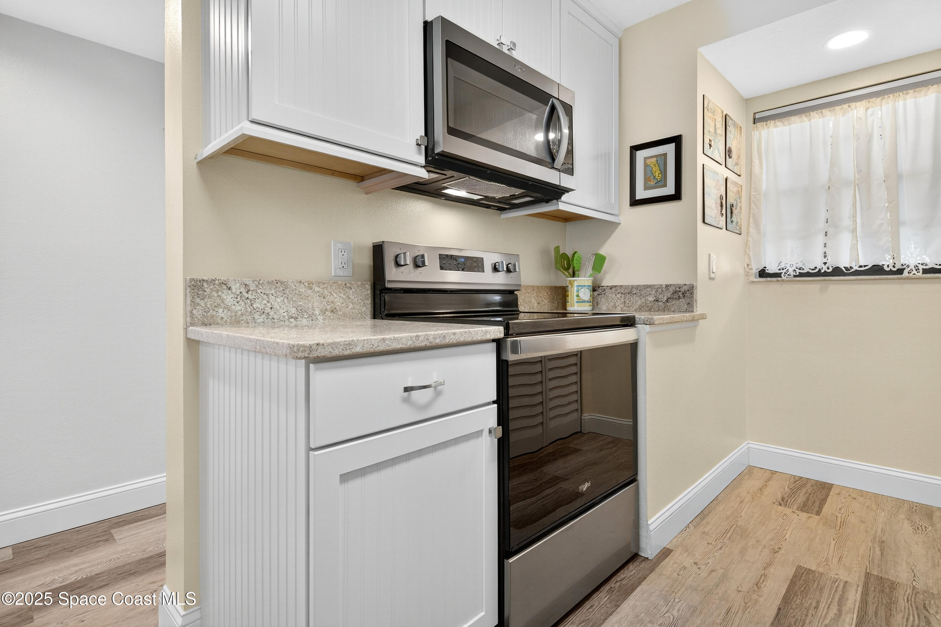 383 North Atlantic Avenue, Unit 105 Cocoa Beach, FL 32931 - Photo 10 of 67 a kitchen with stainless steel appliances granite countertop a refrigerator and a stove top oven