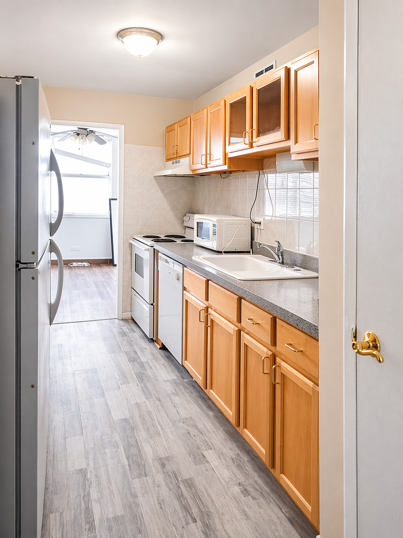6301 North Sheridan Road, Unit 15B Chicago, IL 60660 - Photo 6 of 11 a kitchen with stainless steel appliances granite countertop a sink and wooden cabinets