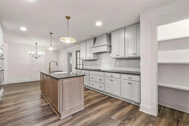 a kitchen with stainless steel appliances granite countertop a sink a stove and a wooden floors