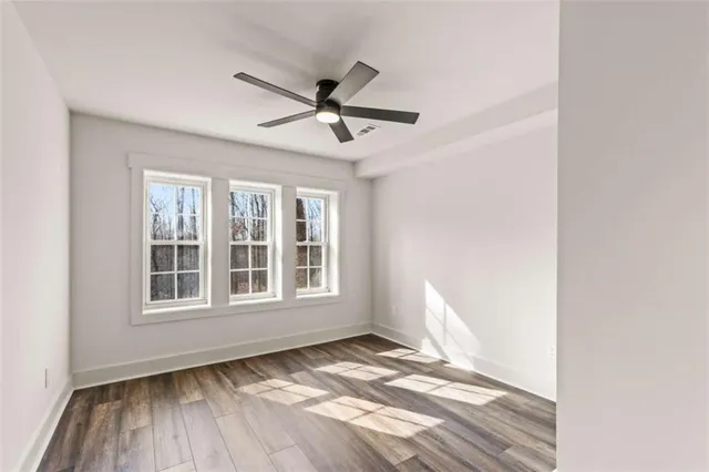 a view of empty room with wooden floor and fan