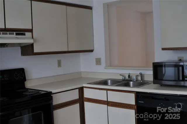 a kitchen with granite countertop a sink stove and microwave