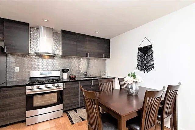 a kitchen with stainless steel appliances a stove a table and chairs