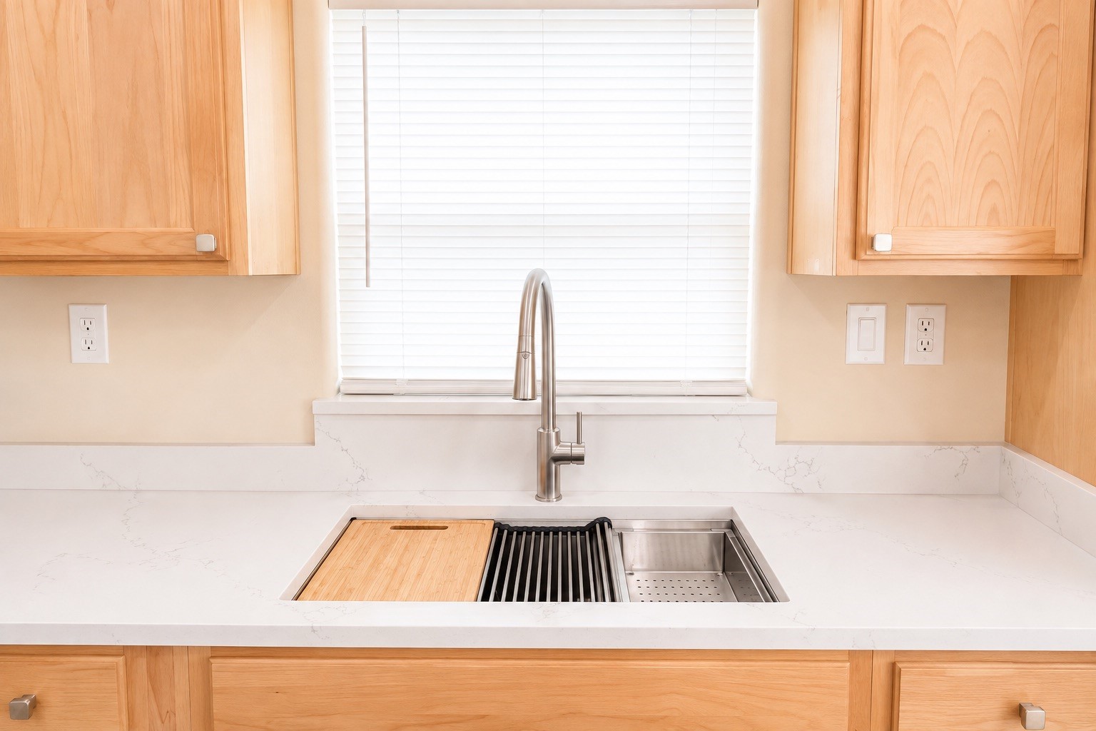 Bright and modern kitchen featuring sleek white countertops, a stylish stainless steel faucet, and warm wood cabinetry for a welcoming touch.