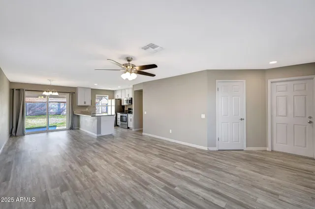 a view of empty room with wooden floor and fan