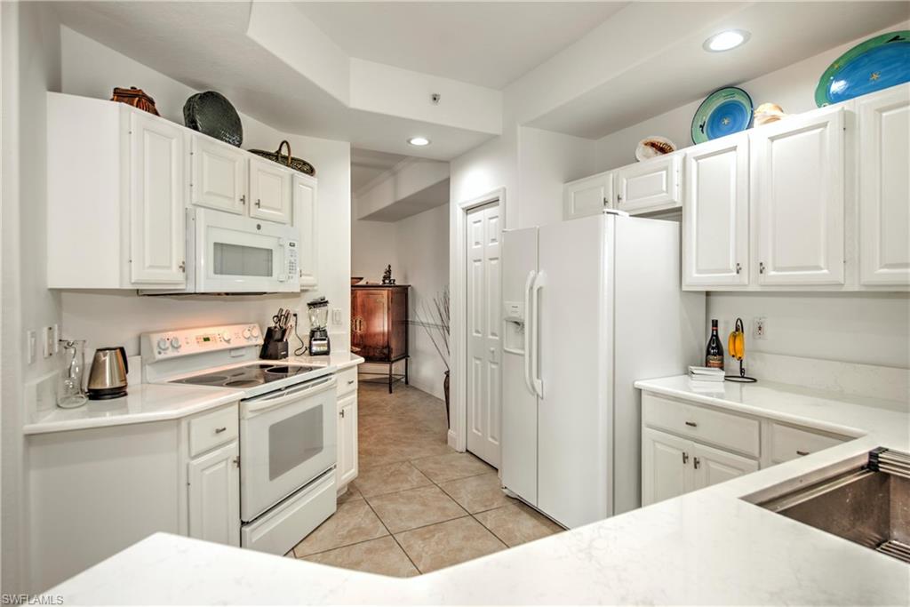8385 Whisper Trace Way, Unit N104 Naples, FL 34114 - Photo 6 of 16 a kitchen with white cabinets and white appliances