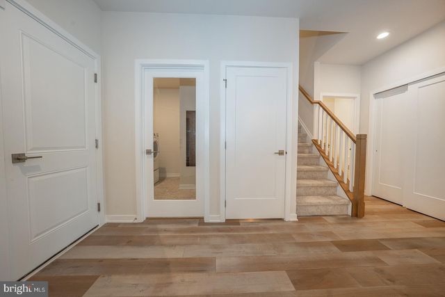 a kitchen with a stove a sink a microwave a refrigerator and white cabinets with wooden floor