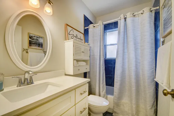 a bathroom with a sink a toilet a mirror and shower curtain