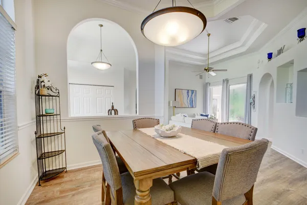 a dining room with wooden floor a chandelier a wooden table and chairs