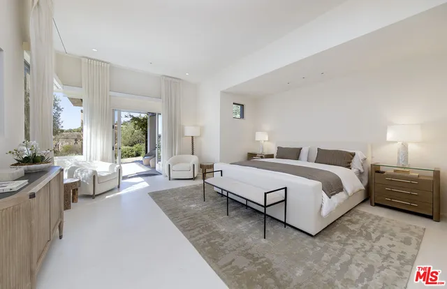 a spacious bedroom with a bed couch and large windows