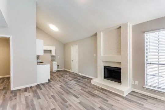 a view of a livingroom with wooden floor and a kitchen