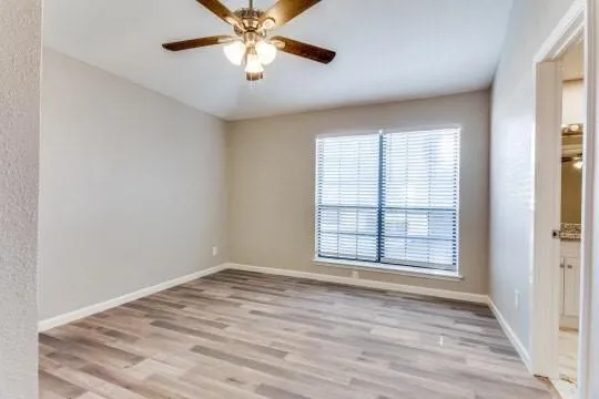 an empty room with wooden floor chandelier fan and windows